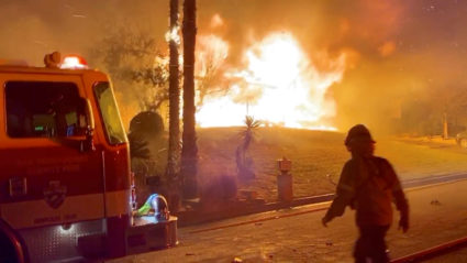 A firefighter passes by a fire engine in front of a burning house during wildfires in San Bernardino, California, on October 31, 2019, in this screen grab obtained from a social media video. 564FIRE via Reuters