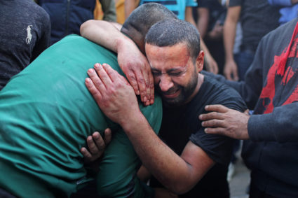 A Palestinian man, stained with the blood of his relative, is comforted as he reacts at Shifa hospital in Gaza City November 13, 2019. Photo by REUTERS/Mohammed Salem