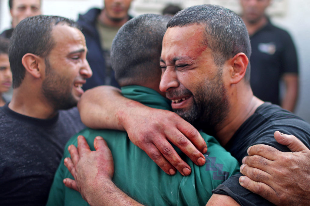 A Palestinian man, stained with the blood of his relative, is comforted as he reacts at Shifa hospital in Gaza City Novemb...