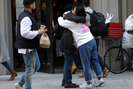 WeWork employees embrace on the sidewalk outside the entrance to the WeWork corporate headquarters in Manhattan, New York, U.S., November 21, 2019. Photo by REUTERS/Mike Segar