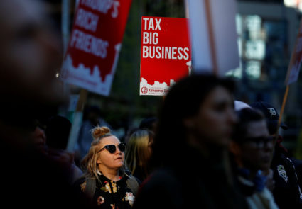 A woman holds a sign supporting the taxation of big businesses during a protest in front of the Amazon Spheres to demand that the city of Seattle tax the largest corporations to help fund affordable housing, according to organizers, in Seattle, Washington, U.S., April 10, 2018. REUTERS/Lindsey Wasson