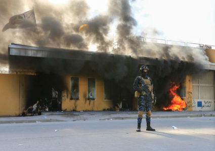 A member of Iraqi security forces stands near burning tyres at the reception room of the U.S. Embassy, during a protest to condemn air strikes on bases belonging to Hashd al-Shaabi (paramilitary forces), in Baghdad, Iraq January 1, 2020. Photo by REUTERS/Thaier al-Sudani