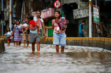 Women carrying their children walk accross the floodwaters at the Jatinegara area after heavy rains in Jakarta, Indonesia, January 2, 2020. Photo by Willy Kurniawan/Reuters