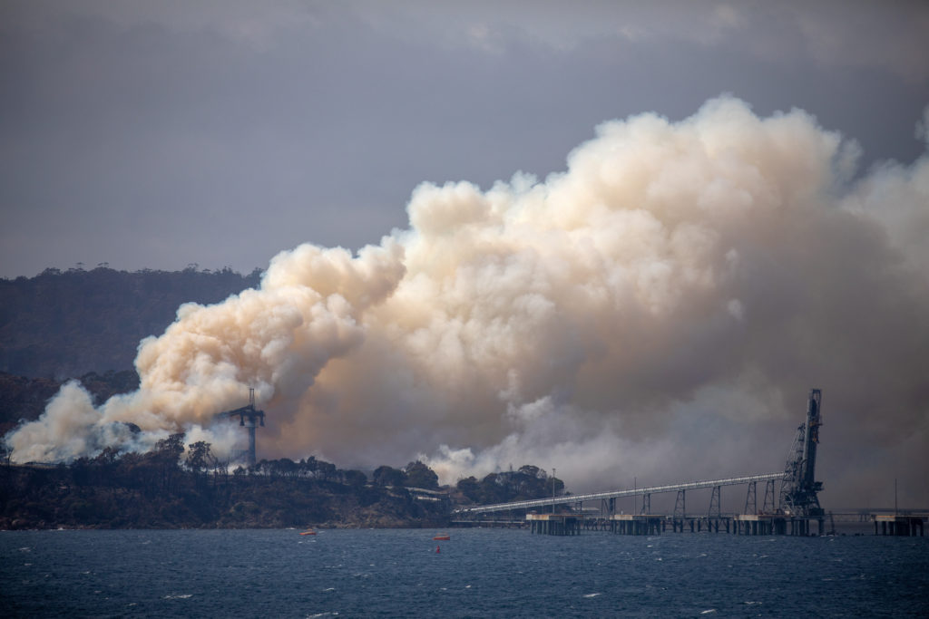 Smoke rises from the Eden Woodchip Mill, from a fire that has been blazing for days, after bushfires came close the previo...