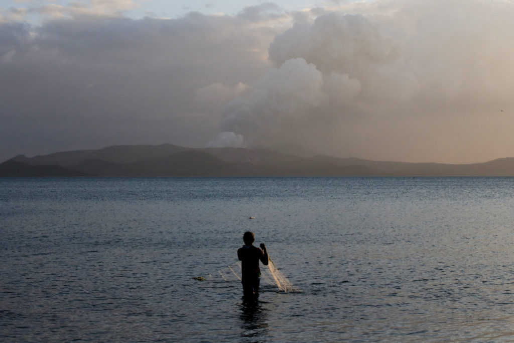 A man catches fish as the Taal Volcano continues to erupt in Talisay, Batangas, Philippines, January 14, 2020. Photo by El...