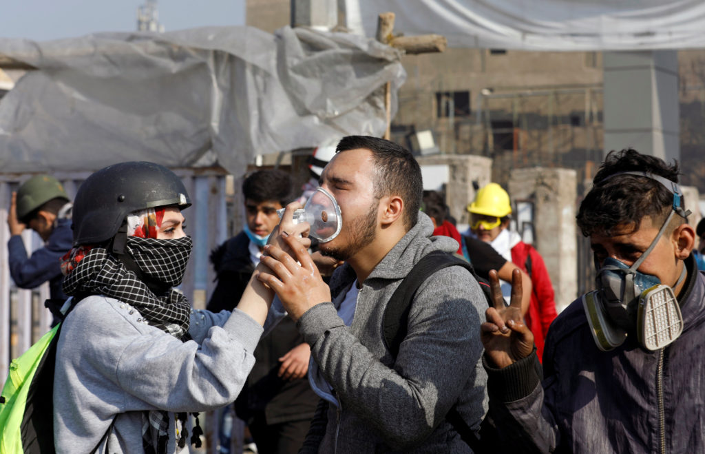 An Iraqi demonstrator receives medical help after being affected by tear gas during ongoing anti-government protests, in B...