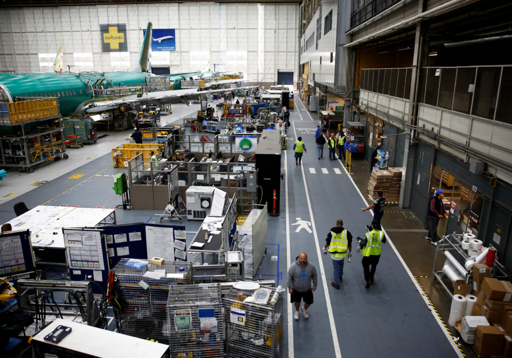 Workers walk by a 737 Max aircraft on the production line at the Boeing factory in Renton, Washington, U.S., March 27, 201...
