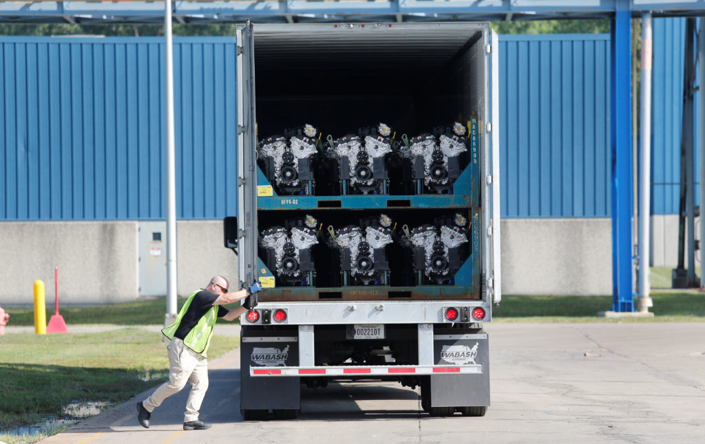 A truck driver closes the door to a transport truck loaded with V6 engines, used in a variety of General Motors cars, truc...