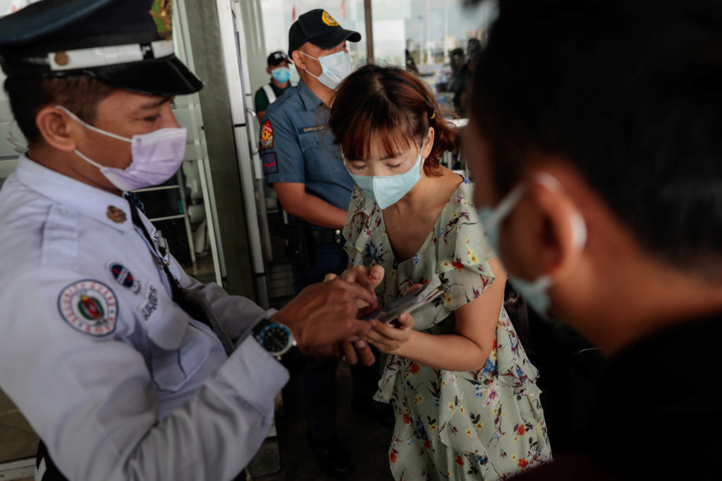 Passengers wearing protective masks, following confirmed cases of coronavirus in the country, arrive at the departure area...