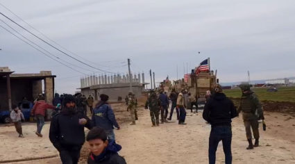 People gather near U.S military vehicles in the village of Khirbet Amo, near Qamishli, Syria February 12, 2020. Photo by SANA/Handout via Reuters