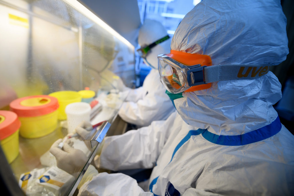 FILE PHOTO: Workers in protective suits conduct RNA tests on specimens inside a laboratory at a centre for disease control...