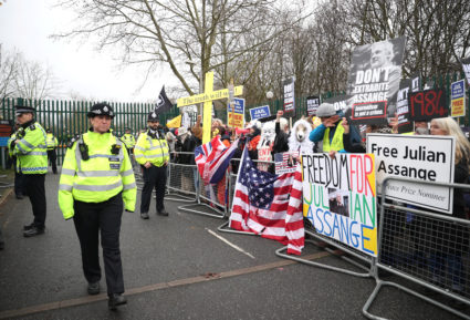 Police officers watch as demonstrators hold signs behind a barricade in support of WikiLeaks founder Julian Assange, outside Woolwich Crown Court, ahead of a hearing to decide whether Assange should be extradited to the United States, in London, Britain, February 24, 2020. Photo by Hannah Mckay/Reuters