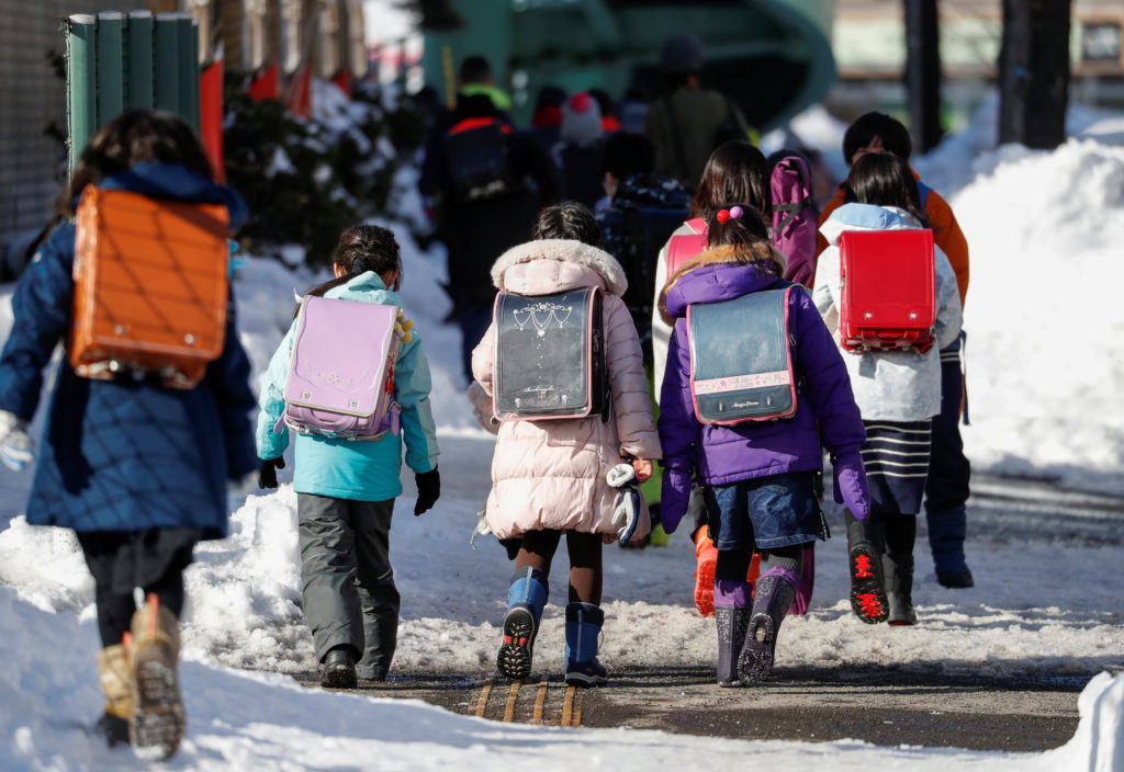 Elementary school students walk on the snow-covered street in Sapporo, Hokkaido, Japan, February 26, 2020. Photo by Issei ...