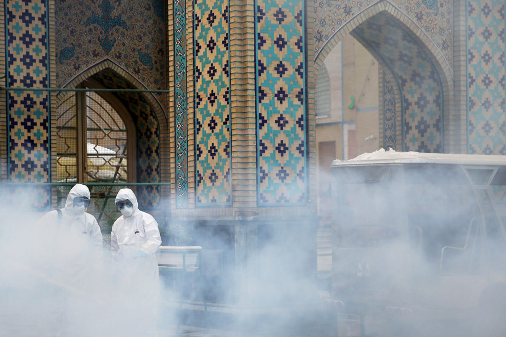 FILE PHOTO: Members of a medical team spray disinfectant to sanitize outdoor place of Imam Reza's holy shrine, following t...