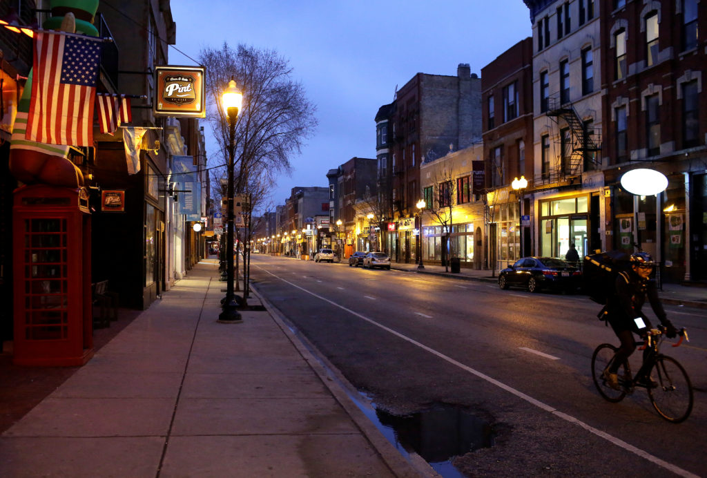 A cyclist rides along empty Milwaukee Avenue as Illinois Governor J.B. Pritzker ordered all restaurants and bars closed at...