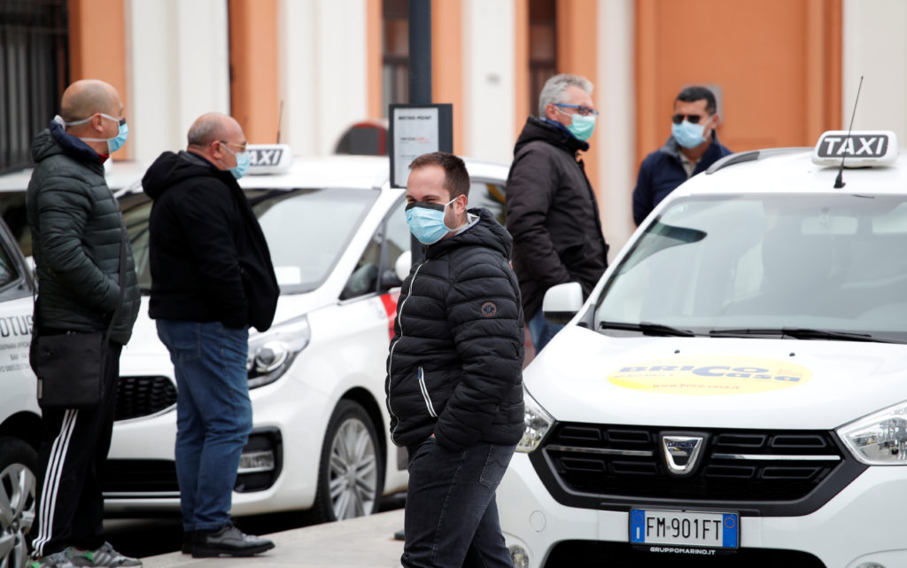 Taxi drivers wearing protective face masks wait for customers outside the Bari Centrale railway station in Bari as the spr...