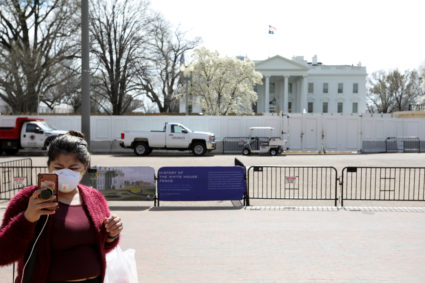 A tourist wearing a face mask takes a picture standing on the pedestrian plaza outside of the White House in Washington, U.S., March 12, 2020. Photo by Jonathan Ernst/Reuters