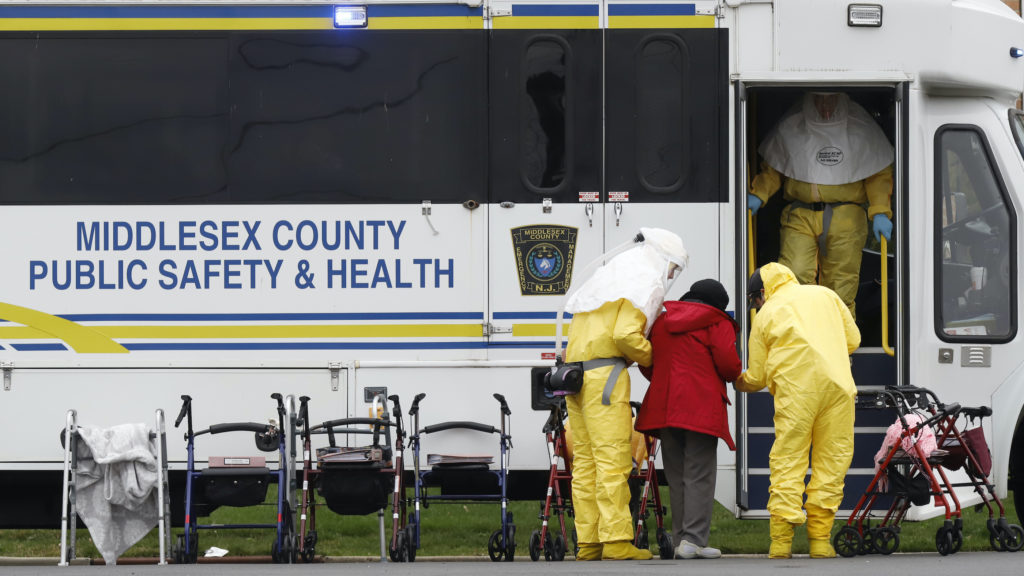 Medical officials aid a residents from St. Joseph's nursing home to board a bus, after a number of residents tested positi...