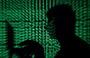 A man holds a laptop computer as cyber code is projected on him in this illustration picture taken on May 13, 2017. Photo by Kacper Pempel/Illustration/REUTERS