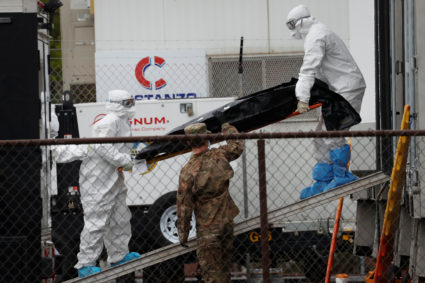 Workers wearing personal protective equipment (PPE) move the body of a deceased person from a refrigerated truck trailer set up at a temporary morgue outside University Hospital during the outbreak of the coronavirus disease (COVID-19) in Newark, New Jersey, U.S., May 6, 2020. Photo by REUTERS/Mike Segar