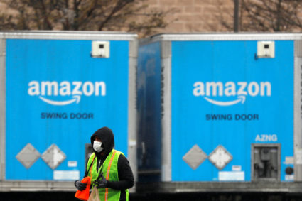 A worker in a face mask walks by trucks parked at an Amazon facility as the global coronavirus outbreak continued in Bethpage on Long Island in New York, U.S., March 17, 2020. Photo by Andrew Kelly/REUTERS