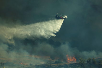 A helicopter drops water on a wind driven wildfire named the Bond Fire near Lake Irvine in Orange County, California, U.S., December 3, 2020. Photo by REUTERS/Mike Blake