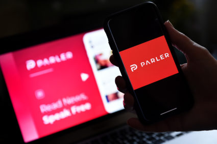 This illustration picture shows social media application logo from Parler displayed on a smartphone with its website in the background in Arlington, Virginia on July 2, 2020. Photo by OLIVIER DOULIERY/AFP via Getty Images