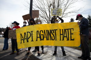 People wave a large "AAPI Against Hate" sign at honking cars during a pre-planned rally against anti-Asian hate crimes held by the Asian American Pacific Islanders Organizing Coalition Against Hate and Bias in Newcastle, Washington, U.S. March 17, 2021. Photo by Lindsey Wasson/REUTERS