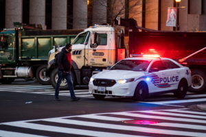 A man walks by a police car and trucks which block the street as they stand guard near the White House ahead of U.S. President-elect Joe Biden's inauguration, in Washington, U.S., January 19, 2021. REUTERS/Eduardo Munoz