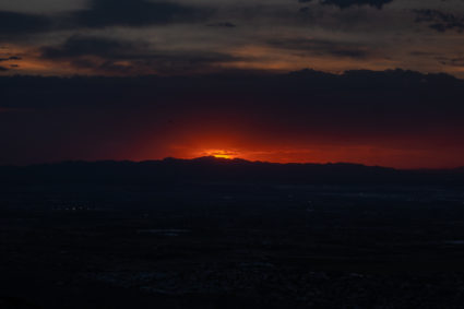 A hazy bright red sunset behind a mountain in Phoenix, Arizona.