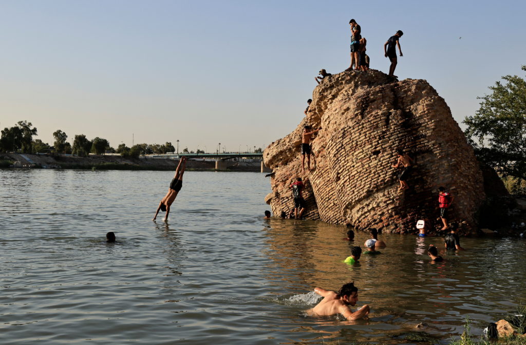 People dive into the Tigris river to cool down in the summer heat, in Baghdad