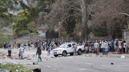 People stand on the roadside after being evicted following protests that have widened into looting, in Durban