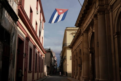 A Cuban flag flies over a street in downtown Havana