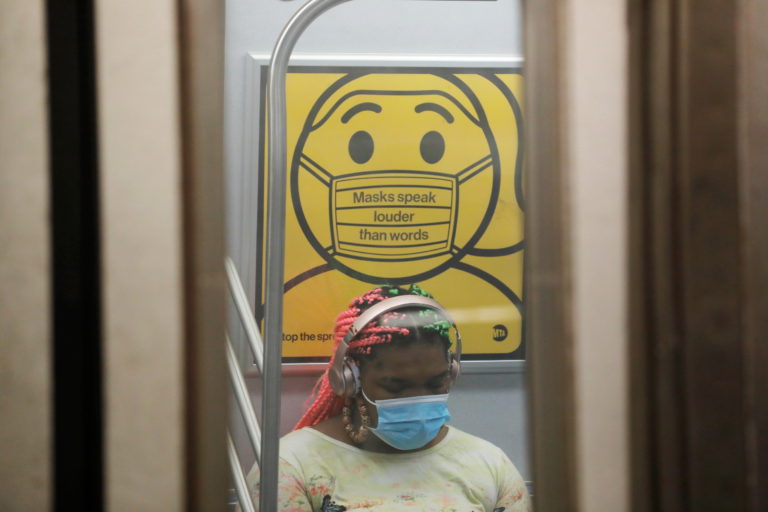 A commuter wears a mask under public safety signage as cases of the infectious coronavirus Delta variant continue to rise ...