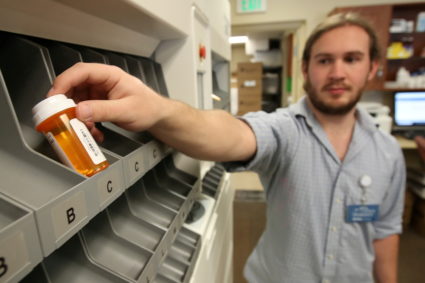 FILE PHOTO: Pharmacist technician McKay Kleinman, holds a filled prescription bottle that came out from an automated drug ...