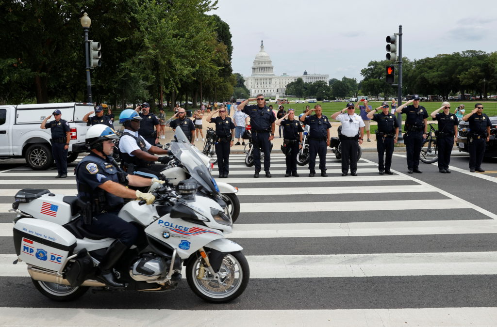 Law enforcement officers salute as a ceremonial procession in honor of a police officer wounded at the Pentagon passes the...