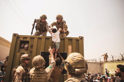 UK coalition forces, Turkish coalition forces, and U.S. Marines assist a child during an evacuation at Hamid Karzai Intern...