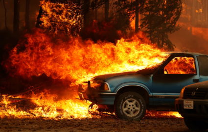 Wind-driven flames shoot horizontally out of the windshield of a car on fire at the Dixie Fire, a wildfire near the town o...