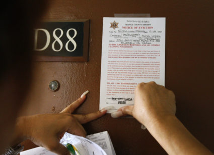 Orange County sheriff's deputy Ramona Figueroa posts an eviction notice on an apartment in Fullerton, California