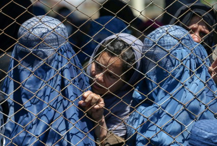 FILE PHOTO: Afghan women wait to receive free wheat donated by the Afghan government during a quarantine, amid concerns ab...