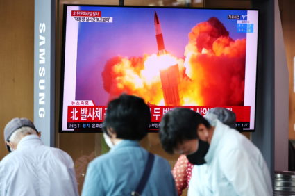 People watch a TV broadcasting file footage of a news report on North Korea firing what appeared to be a pair of ballistic...