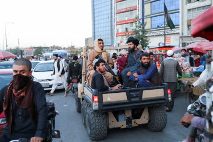 Taliban soldiers sit on the back of a truck in a street in Kabul