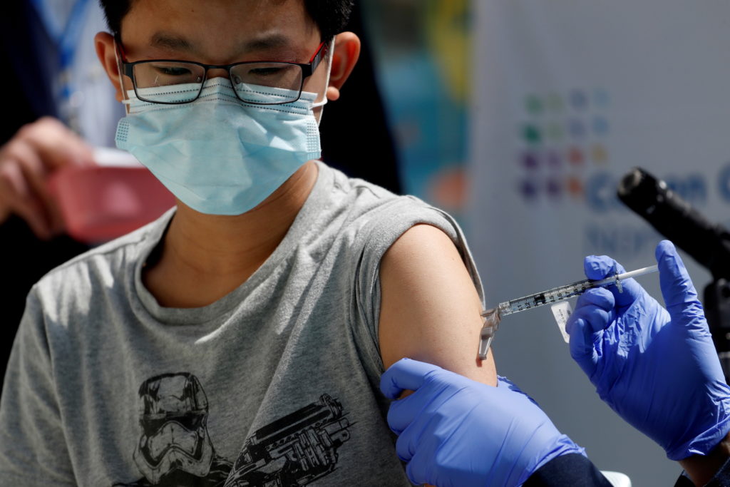 Brendan Lo (13) receives a dose of the Pfizer-BioNTech vaccine for the coronavirus disease (COVID-19) at Northwell Health'...