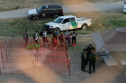 Asylum-seeking migrants wait to be processed under the International Bridge in Del Rio