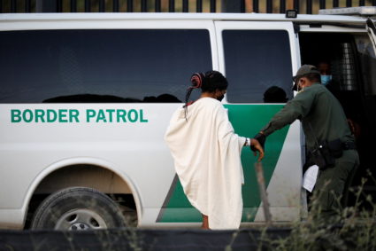 A U.S. Border Patrol officer assists a migrant seeking asylum in the U.S. near the International Bridge between Mexico and...