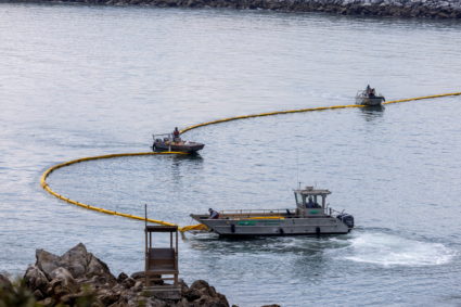 FILE PHOTO: Workers seal off Newport Beach harbor as a major California oil spill moves south down the coast