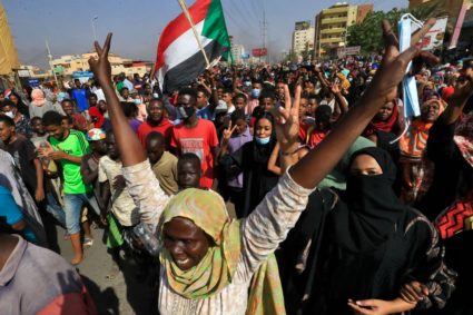 Sudanese protesters lift national flags as they rally on 60th Street in the capital Khartoum, to denounce overnight detentions by the army of government members, on October 25, 2021. - Armed forces detained Sudan's Prime Minister over his refusal to support their "coup", the information ministry said, after weeks of tensions between military and civilian figures who shared power since the ouster of autocrat Omar al-Bashir. (Photo by AFP) (Photo by -/AFP via Getty Images)