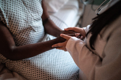 Female doctor holding hands of her patient at hospital room