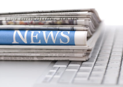 Stack of newspapers resting on laptop keyboard