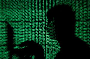 FILE PHOTO: A man holds laptop computer as cyber code is projected on him in this illustration picture